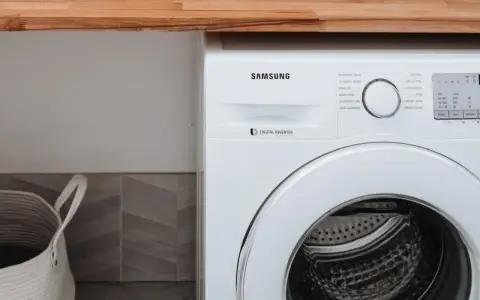 Biała pralka Samsung z technologią Digital Inverter. Obok kosz na pranie.