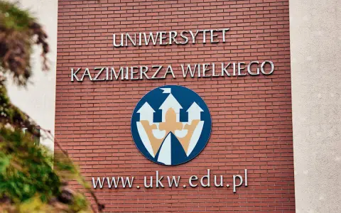 Elewacja Uniwersytetu Kazimierza Wielkiego w Bydgoszczy z logo i adresem strony.