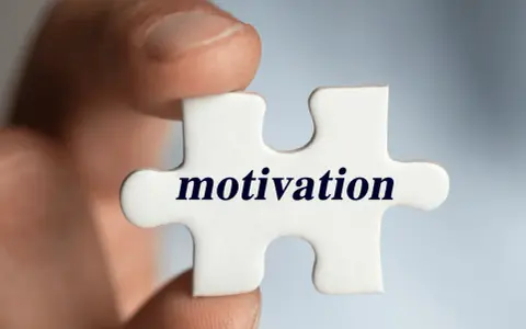Palec trzyma element układanki z napisem "motivation". Klucz do sukcesu i tego, jak motywować pracowników, tkwi w znalezieniu właściwego elementu.