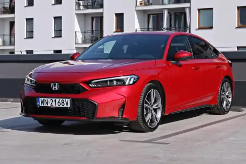 Czerwony Honda Civic Si na parkingu przed nowoczesnym budynkiem. Sportowy wygląd i dynamiczna linia nadwozia.