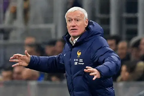 Didier Deschamps, trener Francji, w niebieskiej kurtce z herbem reprezentacji, gestykuluje na boisku.