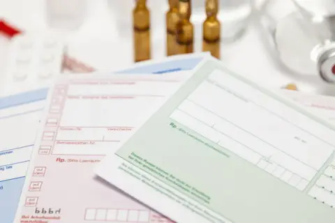 Mehrere medizinische Rezepte und Ampullen liegen auf einem weißen Tisch.