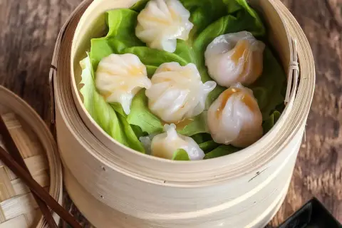 Délicieux ravioli crevette italien, cuits à la vapeur dans un panier en bambou, servis sur des feuilles de laitue.