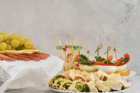 Niskokaloryczne przekąski: roladki z tortilli, jajka faszerowane, winogrona, ser i salami.