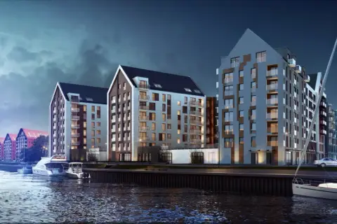 Nowoczesne apartamentowce nad wodą w Gdańsku, przy ulicy Chmielnej. Widok z rzeki na budynki i zacumowane jachty.