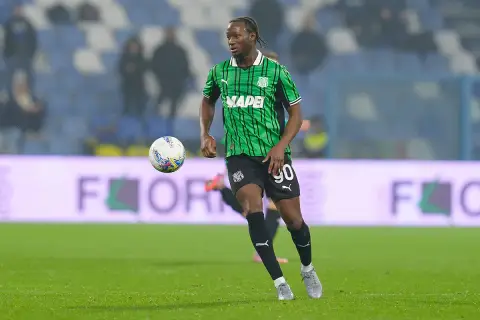 Piłkarz Sassuolo w zielono-czarnej koszulce z numerem 90 biegnie z piłką.