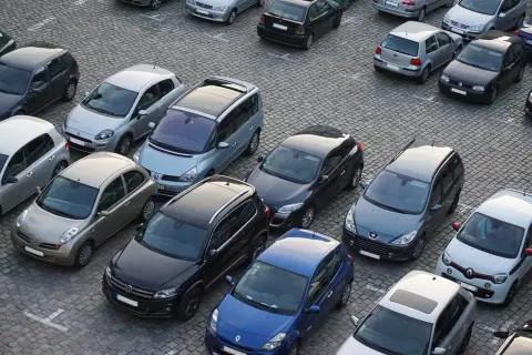 Parking tylko dla mieszkańców, mandat grozi za parkowanie. Wiele samochodów na brukowanym placu.