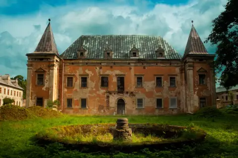 Zrujnowany pałac z wieżyczkami, porośnięty mchem i otoczony bujną zielenią. Kruszyna historii w zapomnianym miejscu.