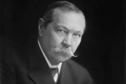 Sir Arthur Conan Doyle, kto jest autorem książek o Sherlocku Holmesie, na czarno-białym portrecie.