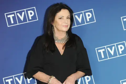 Zofia Czernicka w czarnej kreacji, z okazałą biżuterią, na tle logo TVP. Wiele osób zastanawia się, kim są jej partnerzy.