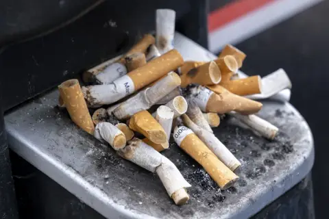 Kupa niedopałków papierosów w popielniczce. Zastanawiasz się, ile kosztują papierosy we Francji?