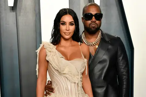 Kim Kardashian i jej mąż, Kanye West, pozują do zdjęć w eleganckich strojach.