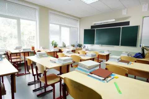 Puste ławki i stosy książek w sali lekcyjnej, jakby właśnie skończył się rok szkolny.