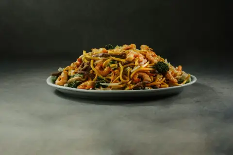 Talerz pełen aromatycznego, smażonego makaronu z krewetkami, wołowiną i brokułami.