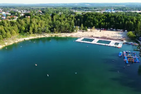 Letni dzień nad wodą w Trzebini. Ludzie odpoczywają na plaży i pływają w jeziorze, które przypomina Balaton.