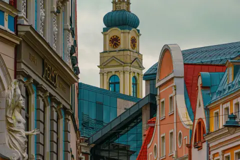 Architektura Rygi zachwyca. Zobaczysz tu zabytkowe kamienice i nowoczesne budynki, a w oddali wieżę zegarową.