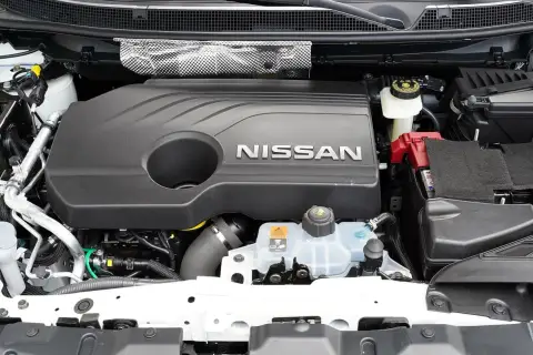 Silnik Nissana Qashqai J11, z widocznym napisem NISSAN na czarnej osłonie. Widać akumulator i zbiornik płynu chłodniczego.