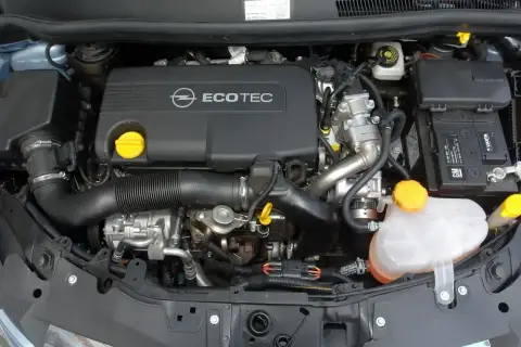 Silnik Opel Corsa D 1.2 benzyna. Widoczny jest czarny dekiel z napisem Ecotec, akumulator Varta oraz zbiornik płynu chłodniczego.