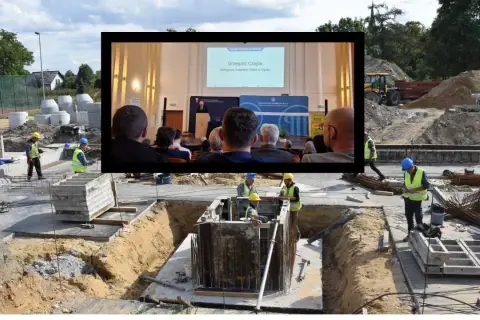 Budowa postępuje powoli, jakby dotknięta skutkami nadmiernego planowania w Excelu (worldbuilder's disease). Na placu budowy widać robotników, a w tle ekran z prezentacją.