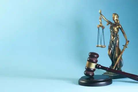 Młotek sędziowski i Temida na tle, symbolizujące sprawiedliwość i prawo, gdzie każdy weksel ma swoją wagę.