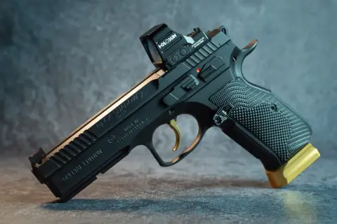 Czarny pistolet CZ Shadow 2 Special Edition z celownikiem Holosun i złotym przedłużeniem magazynka. Ten pistolet sygnałowy to marzenie kolekcjonera.
