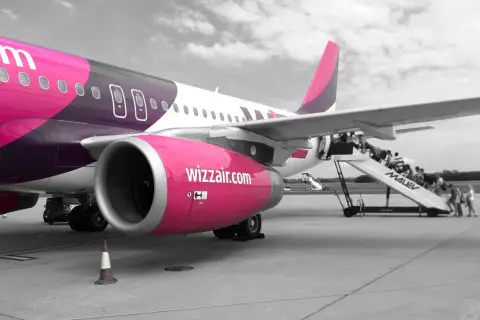 Samolot Wizzair na płycie lotniska. Pasażerowie wsiadają po schodkach. Zastanawiasz się, jak odwołać lot Wizzair?