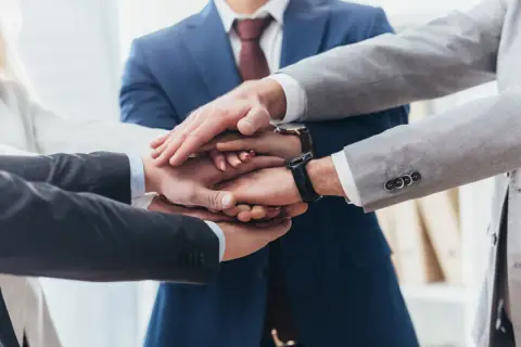 Zespół składa dłonie, symbolizując jedność i siłę. To jak prokura samoistna – wspólne działanie dla dobra firmy.