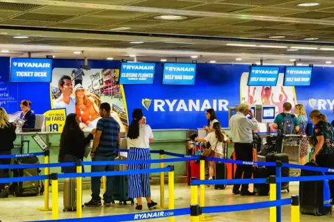 Odprawa na lotnisku Ryanair. Pasażerowie czekają w kolejce do stanowiska odprawy bagażu i biletów.