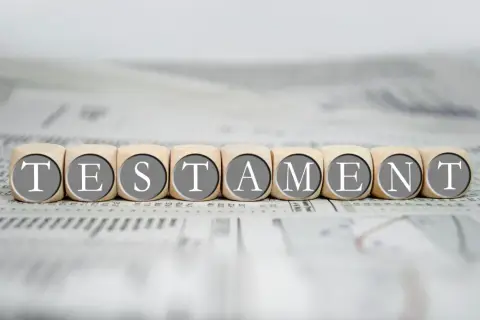 Drewniane klocki z literami tworzą słowo "TESTAMENT", symbolizując prawo dziedziczenia i testament.