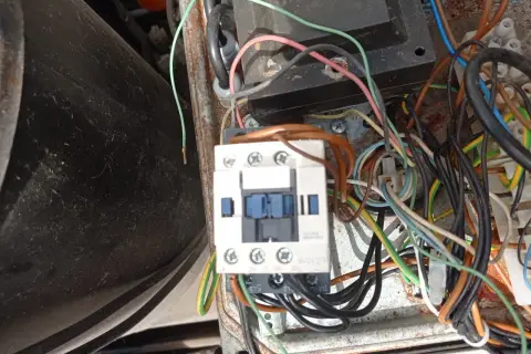Widok z bliska na wyłącznik silnikowy Schneider z licznymi przewodami w skrzynce elektrycznej.