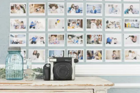 Instax aparat i ściana pełna wspomnień. To idealne miejsce, by zacząć naukę podstaw fotografii i uwieczniać ważne chwile.