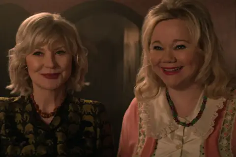 Uśmiechnięte twarze aktorek z "Chilling Adventures of Sabrina obsada". Jedna w żakiecie w słonie, druga w różowym kardiganie.