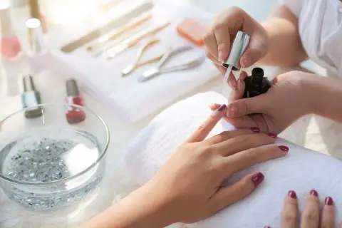 Manicure tytanowy krok po kroku: aplikacja lakieru na paznokcie, narzędzia do stylizacji w tle.