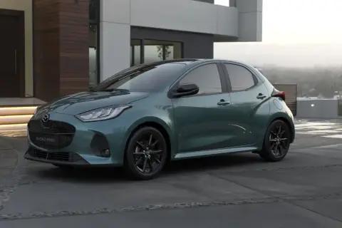 Elegancka, zielona Mazda 2 Hybrid stoi przed nowoczesnym domem.