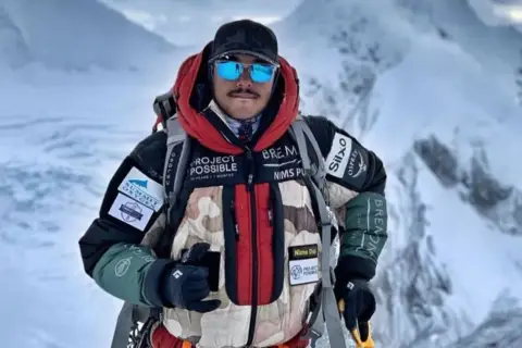 Nims Dai, alpiniste audacieux, porte sa veste "Project Possible" sur les sommets enneigés.