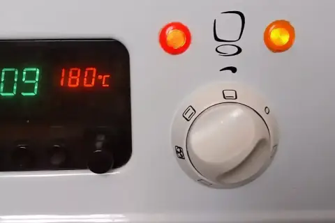 Piekarnik Mastercook: cyfrowy wyświetlacz pokazuje 180°C, a pokrętła sterują funkcjami. Czerwona lampka sygnalizuje pracę.