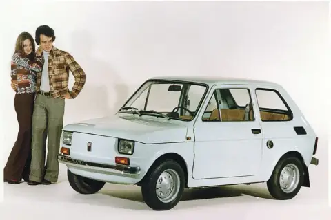 Para młoda pozuje obok białego Fiata 126p Bis.