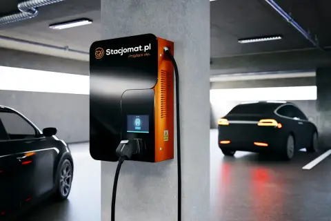 Stacja ładowania samochodu elektrycznego w garażu podziemnym. Nowoczesna ładowarka Stacjomat.pl gotowa do podłączenia pojazdu.