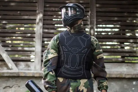 Gracz w kamizelce ochronnej i masce, gotowy do gry. Tak się ubiera na paintball, by czuć się bezpiecznie i komfortowo.