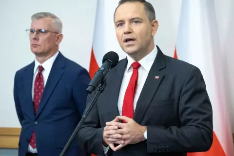 Mężczyzna w garniturze mówi do mikrofonu, obok stoi drugi mężczyzna. Dyskutują, dlaczego prezydent chce zwiększenia budżetu na Biuro Bezpieczeństwa Narodowego o 15 procent.