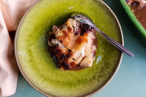Un délicieux crumble poire chocolat, doré et croustillant, servi dans une assiette verte avec une cuillère.