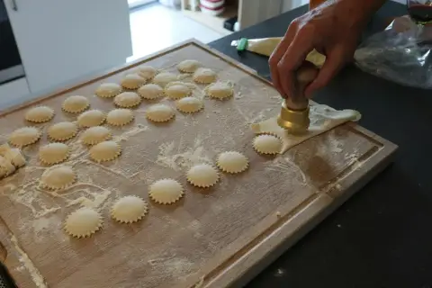 Ręcznie robione ravioli z pysznym farszem do ravioli, przygotowywane na drewnianej desce.