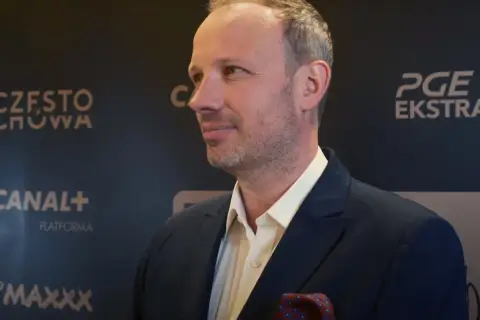 Marcin Majewski z TVN w eleganckim garniturze, na tle logotypów PGE Ekstraklasa i Canal+.