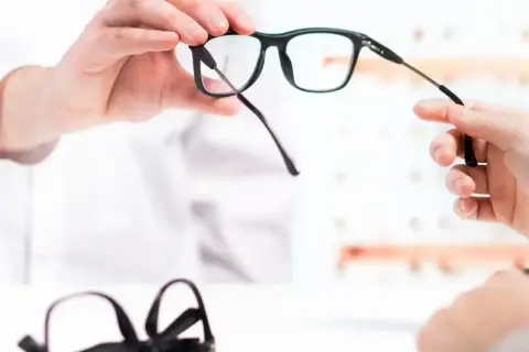 Pracodawca oferuje refundację okularów. Dwie pary okularów, jedna w rękach, druga na stole.