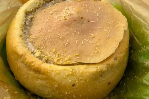Formaggio casu marzu, con la sua crosta dorata e il ripieno cremoso, pronto per essere gustato.