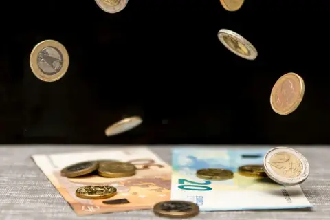 Monety euro spadają na banknoty 50 i 20 euro. To symboliczna scena pokazująca portugalia waluta w ruchu.