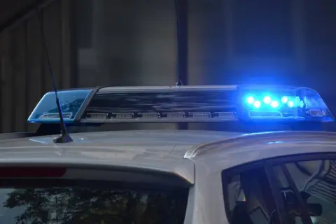 Niebieskie światła pojazdu uprzywilejowanego migają na dachu radiowozu.
