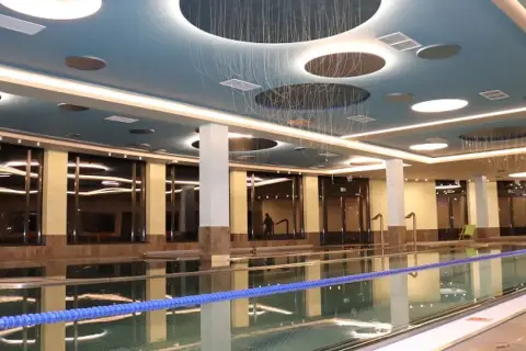Nowoczesny basen w słowackich termach z błękitnym sufitem i designerskim oświetleniem.