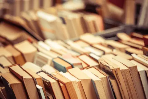 Stosy książek, które inspirują do zastanowienia, czy audiobooki zmieniają sposób, w jaki odbieramy świat przedstawiony.