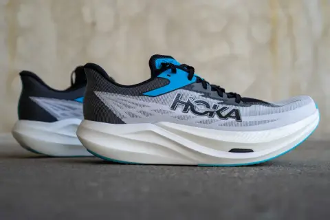 Zwei Hoka Rocket X3 Laufschuhe in Grau mit blauen Akzenten und weißer Sohle stehen nebeneinander.